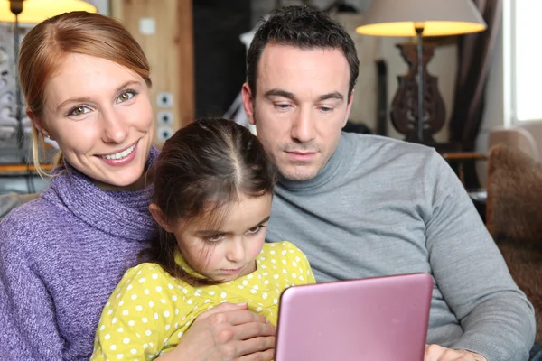 Pais e filha sentaram-se com laptop no sofá — Fotografia de Stock