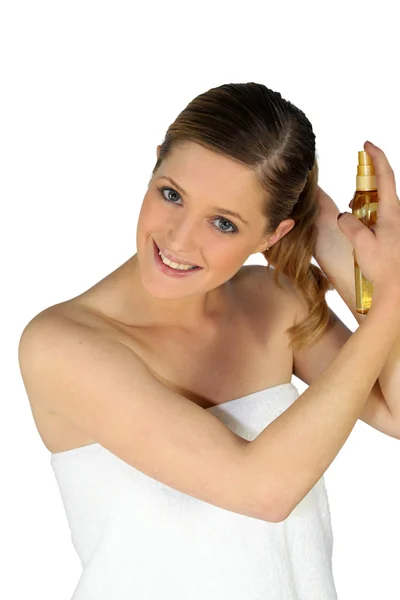 Frau sprüht sich Haare mit einem Produkt — Stockfoto