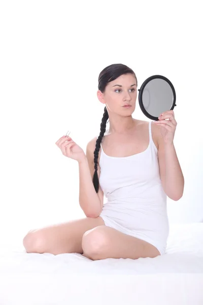 Mladá žena seděla na posteli, drží zrcadlo — Stock fotografie