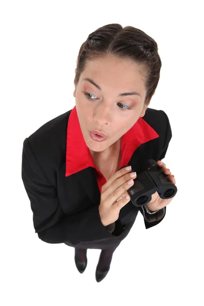 Curious businesswoman holding binoculars — Stock Photo, Image