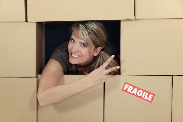Mujer en una pared de cajas de cartón — Foto de Stock