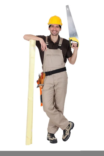 Tradesman holding a saw and a plank of wood — Stock Photo, Image