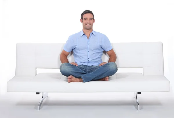 Молодий чоловік сидить на білому дивані — стокове фото
