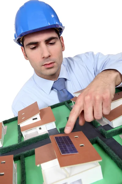 Архітектор, що вказує на сонячну панель на модельному будинку — стокове фото