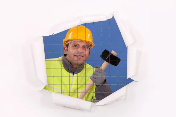 A man with a sledgehammer behind a wire netting. — Stock Photo, Image
