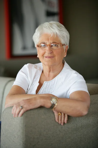 Older woman sitting on a sofa — Stock Photo, Image