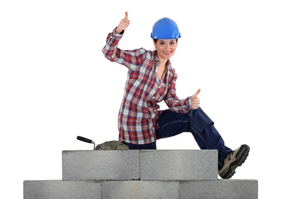 Female mason sitting on a wall making thumbs up sign — Stock Photo, Image