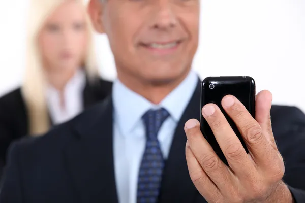 Hombre usando un celular con su asistente en el fondo — Foto de Stock