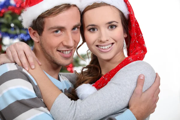 Casal festivo abraçando pela árvore de Natal — Fotografia de Stock
