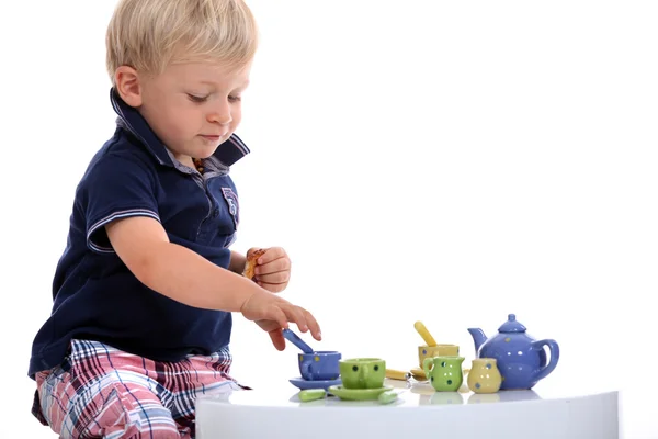 Liten pojke leker med en docka teservis — Stockfoto