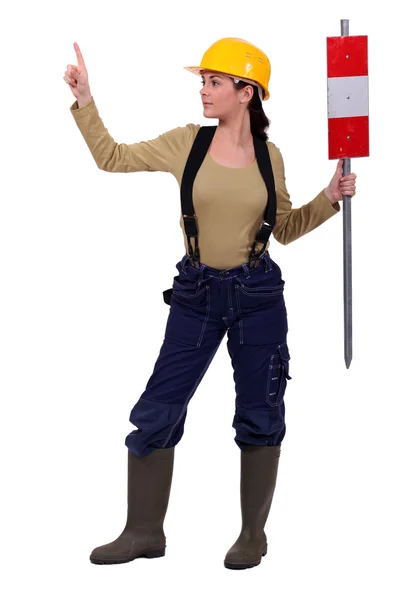 Female helmeted worker holding construction sign — Stok fotoğraf