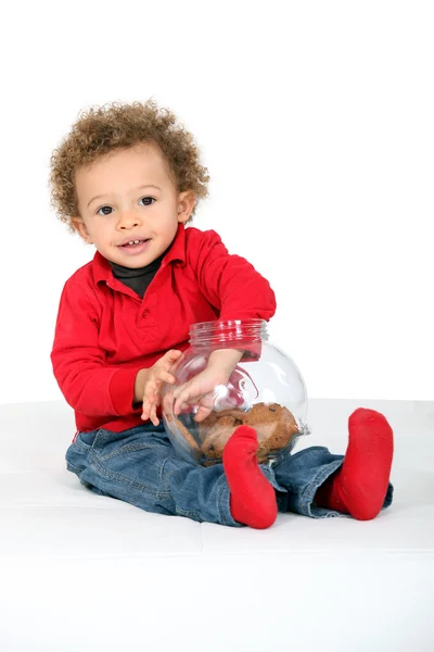 Ребенок с рукой в банке для печенья — стоковое фото