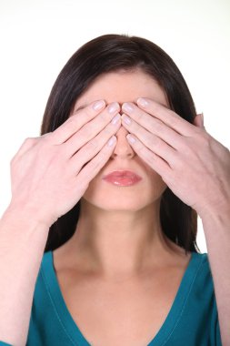 Brunette woman with her hands over her eyes clipart