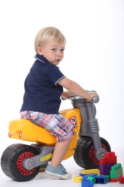 Boy on a toy motorbike clipart