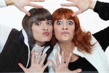 Two women pressing their faces against glass clipart