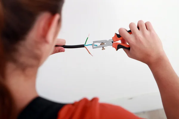 Una electricista hembra pelando un cable . — Foto de Stock