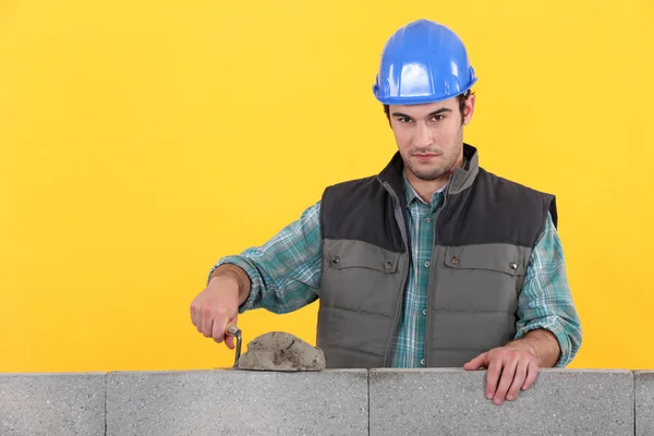 Hombre con paleta esparciendo cemento en la pared —  Fotos de Stock