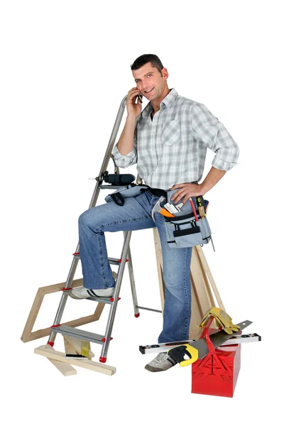 Carpenter stood by equipment making call — Stock Photo, Image