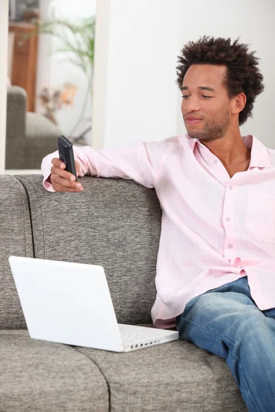 Giovane uomo sms mentre sedeva sul divano — Foto Stock