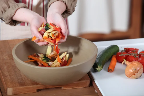 Kvinna sätta vegetabiliska peeling i skål — Stockfoto