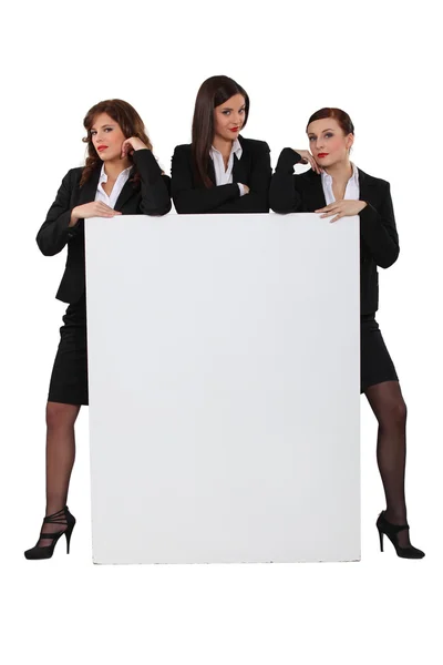 Mulheres de negócios atrevidas com um quadro deixado em branco para a sua mensagem — Fotografia de Stock