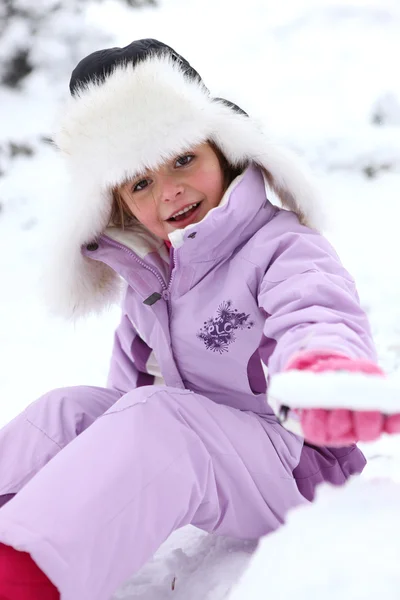 Dziewczynka siedzi na śniegu — Zdjęcie stockowe