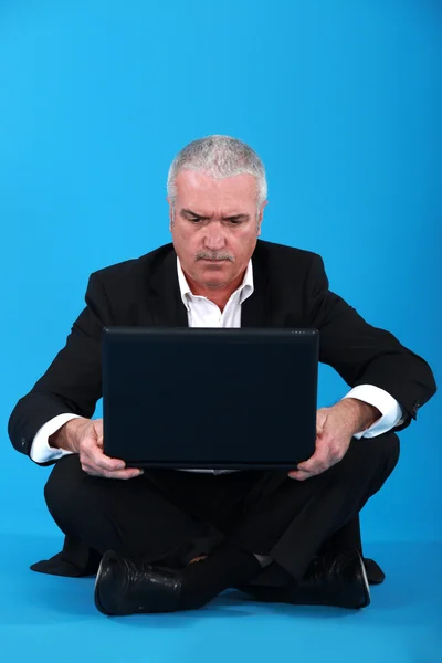 Старший бизнесмен сидел на полу с ноутбуком — стоковое фото