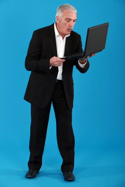Homme d'affaires aux cheveux gris tenant un ordinateur portable — Photo