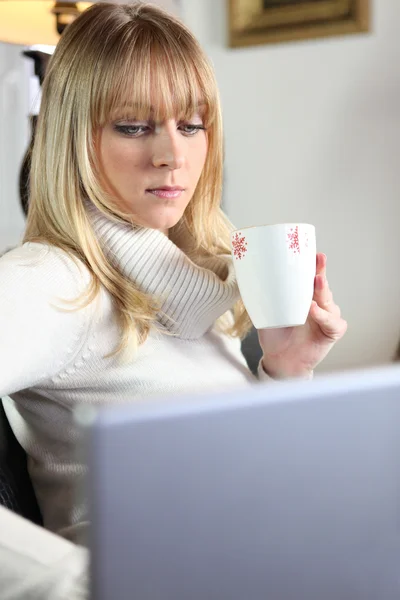 Dizüstü bilgisayarda çalışırken kahve olan tatlı bir genç sarışın — Stok fotoğraf