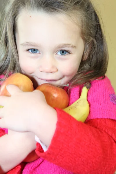Little girl holding fruits in her arms — Stock Photo, Image