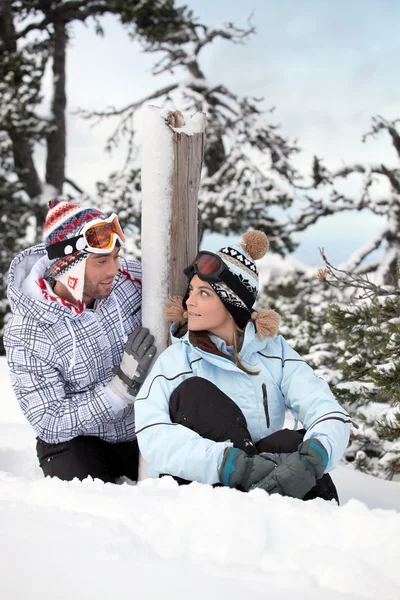 Jeune couple assis sur la neige — Photo
