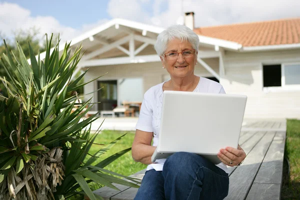 Starsza pani Siedzieliśmy na zewnątrz domu z laptopem — Zdjęcie stockowe