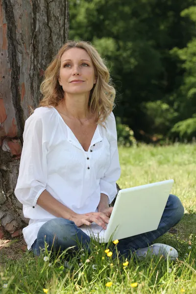 女子坐在一台计算机与草 — 图库照片