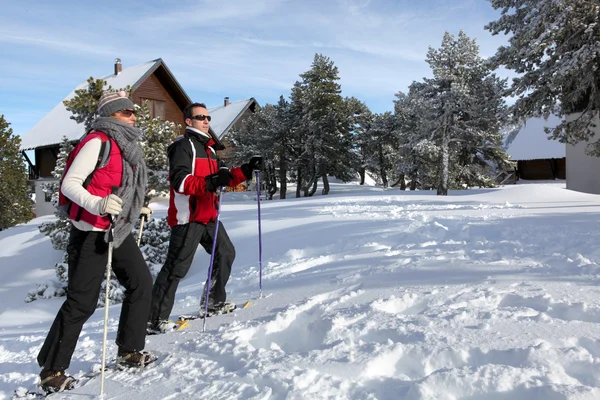 Couple skiing by chalets Stock Image