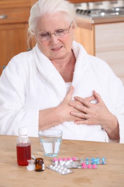 Elderly lady taking her medication clipart