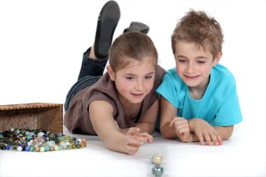 Brother and sister playing marbles together clipart