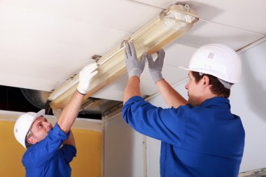 Two electrician repairing office lighting clipart