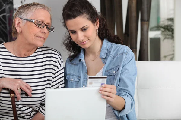 Homecare ajudando a mulher idosa em fazer compras on-line — Fotografia de Stock