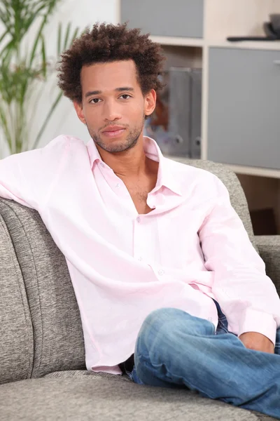 Junger Mann sitzt auf einer Couch — Stockfoto