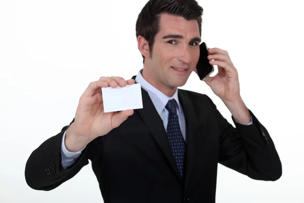 Empresario en el teléfono mientras muestra una tarjeta en blanco —  Fotos de Stock