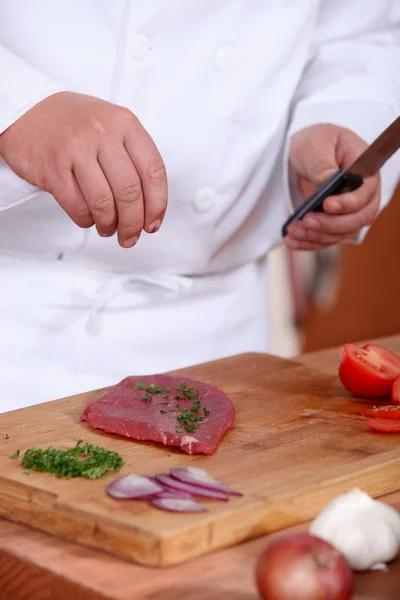 Man putting herbs on a piece of meat — Stock Photo, Image