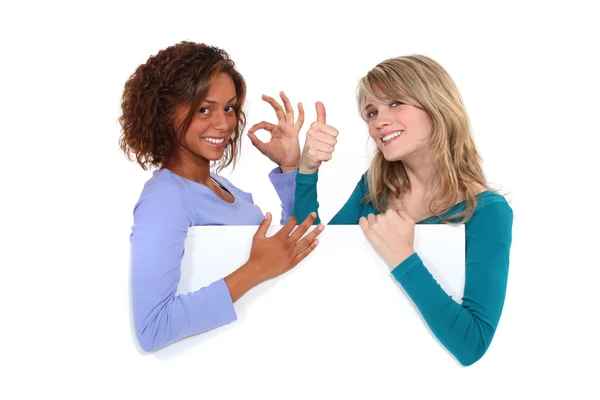 Meninas satisfeitas por trás placa branca — Fotografia de Stock