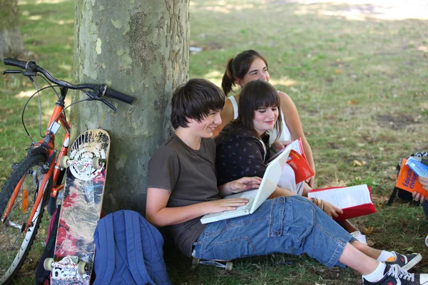 Teenageři sedí u paty stromu — Stock fotografie