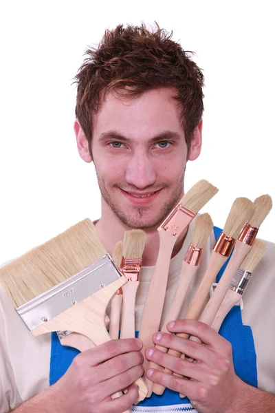 Young man with a selection of decorating paint brushes — Stock Photo, Image