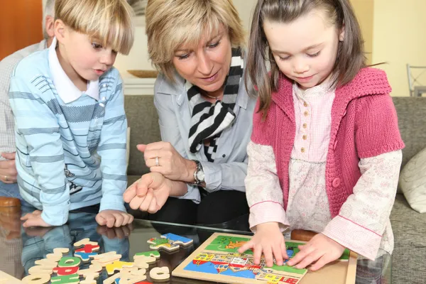 Woman and children with a wooden puzzle — Stock Photo, Image