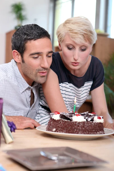 Couple blowing birthday candle — Stock Photo, Image