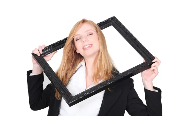 Mujer bonita poniendo su cabeza a través de un marco de imagen — Foto de Stock