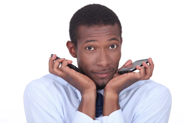 Hombre buscando confundido sosteniendo dos teléfonos móviles — Foto de Stock