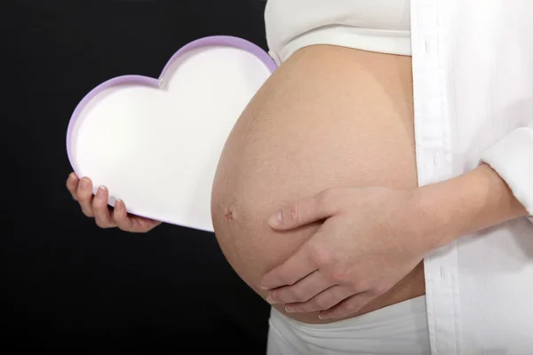 Femme enceinte avec une boîte en forme de coeur — Photo