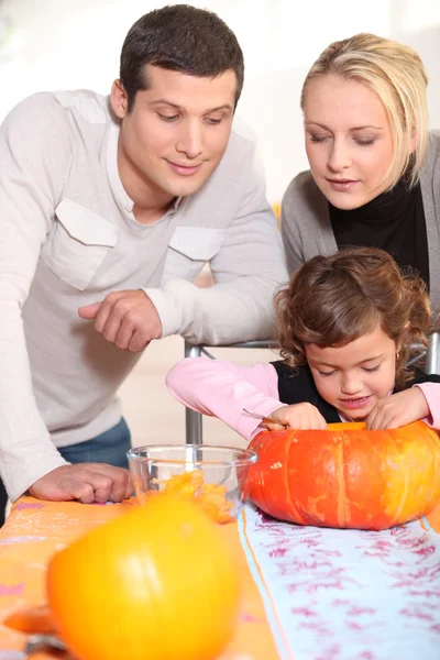 Liten flicka och föräldrar snidning pumpa till halloween — Stockfoto